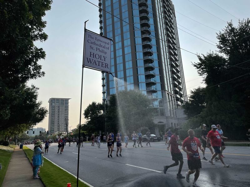 A misting station at the Episcopal Cathedral of St. Philip dowses Atlanta Journal-Constitution Peachtree Road Race participants with holy water on Saturday, July 3, 2021. (Photo: Anjali Huynh/AJC)