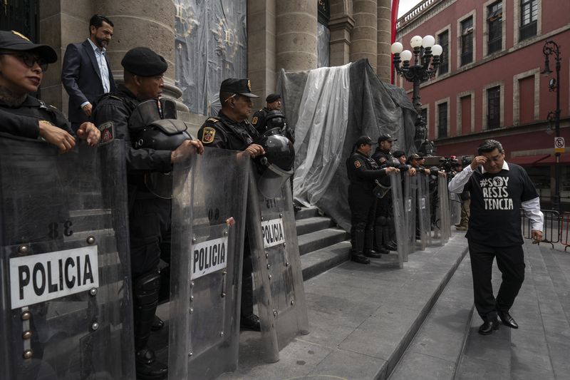 Mexico City legislator, of the National Action Party, Diego Garrido, walks past police who guard the Mexico City Congress amid judicial reform, Thursday, Sept. 12, 2024. (AP Photo/Felix Marquez)