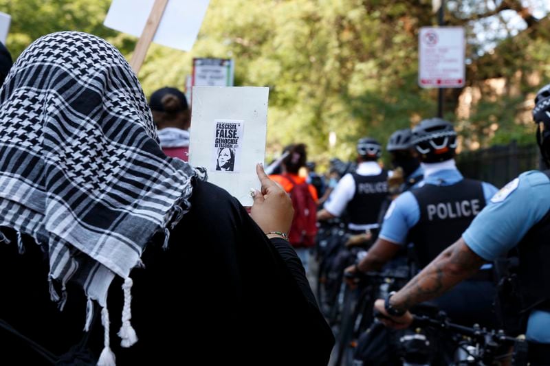 A pro-Palestinian protester at the March on DNC holds a small poster that includes an image of Democratic presidential nominee Kamala Harris with the words "Genocide is Fascism" on Monday, Aug. 19, 2024, in Chicago. Protesters want Vice President Harris to push harder for a cease-fire and to persuade President Biden to end aid to Israel. (AP Photo/Martha Irvine)