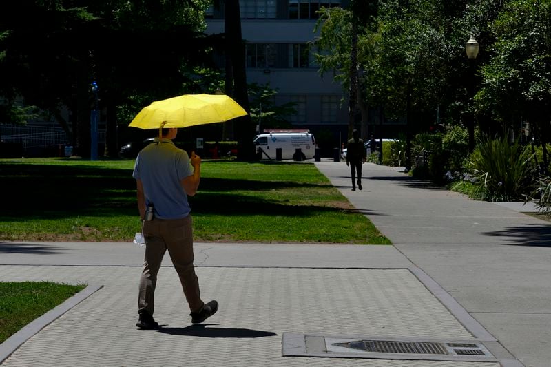 A man shields himself from the sun in Sacramento, Calif., Tuesday, July 2, 2024. . (AP Photo/Terry Chea)