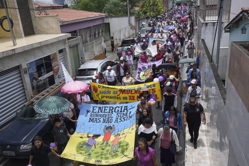 Local farmers and environmental activists march while holding a banner that reads in Portuguese, "Yes to renewable energy but not like this," during a protest asking for new rules for the licensing of wind energy projects, in Areial, Paraiba state, Brazil, Friday, March 15, 2024. (AP Photo/Andre Penner)