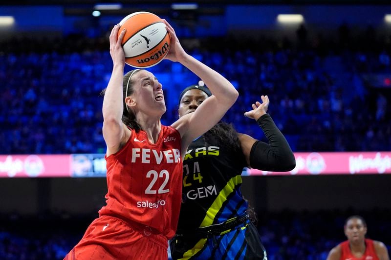 Indiana Fever guard Caitlin Clark (22) leaps to the basket for a shot as Dallas Wings' Arike Ogunbowale (24) defends in the first half of a WNBA basketball game Sunday, Sept. 1, 2024, in Arlington, Texas. (AP Photo/Tony Gutierrez)