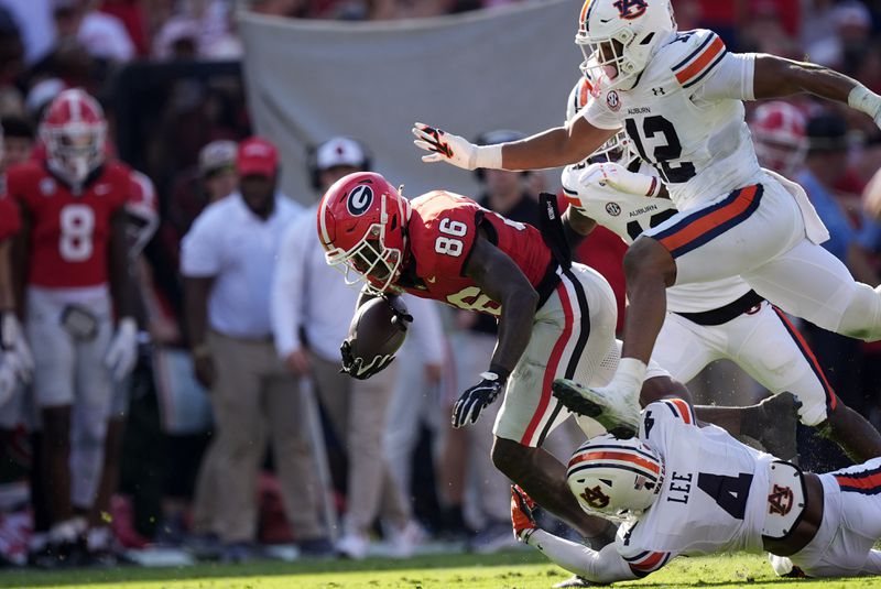 Georgia wide receiver Dillon Bell (86) is brought down by Auburn defen denders Kayin Lee (4) and Dorian Mausi Jr. (12) in the first half of an NCAA college football game Saturday, Oct. 5, 2024, in Athens, Ga. (AP Photo/John Bazemore)