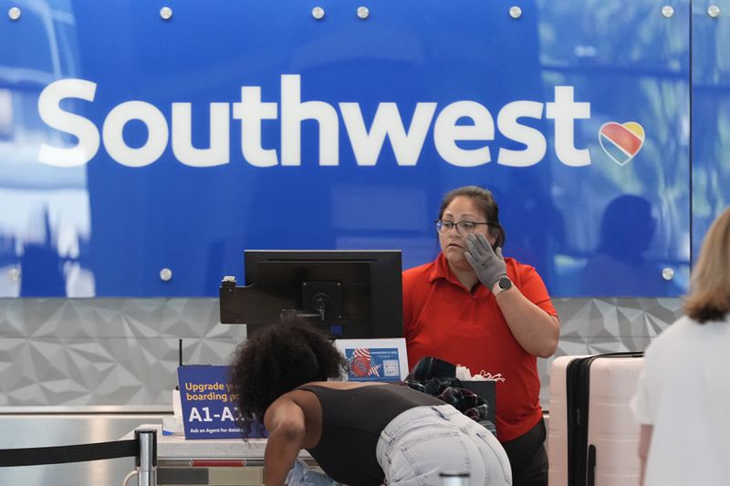 FILE - A Southwest Airlines ticket agent checks in passengers at Love Field in Dallas, July 25, 2024. (AP Photo/LM Otero, File)