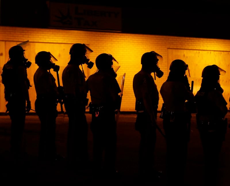 FILE - Police wait to advance after tear gas was used to disperse a crowd during protests against the shooting death of Michael Brown Jr. on Aug. 17, 2014 in Ferguson, Mo. (AP Photo/Charlie Riedel, File)