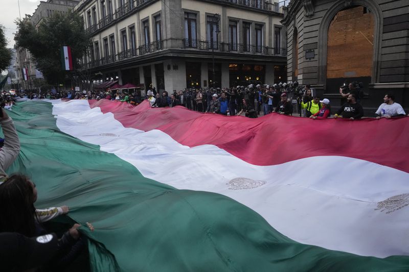 Judicial workers unfurl a Mexican flag to protest the government's proposed judicial reform, which would make judges stand for election, in Mexico City, Tuesday, Sept. 10, 2024. (AP Photo/Eduardo Verdugo)