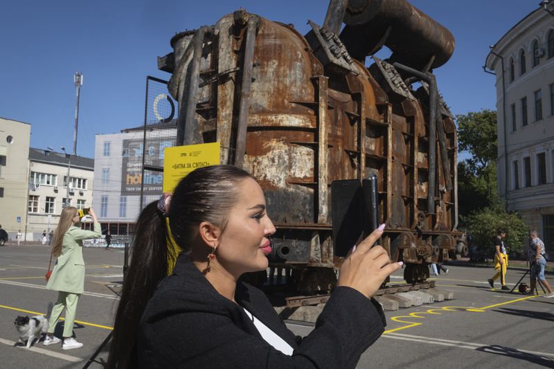 People take photos of a burnt transformer from one of power plants badly damaged in one of Russia's recent missile attacks on energy system in Kyiv, Ukraine, Thursday, Sept. 19, 2024. (AP Photo/Efrem Lukatsky)