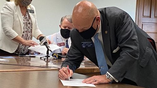 Senate Majority Leader Mike Dugan, R-Carrollton, signs the fiscal 2021 budget deal that cuts state spending by $2.2 billion. James Salzer/james.salzer@ajc.com