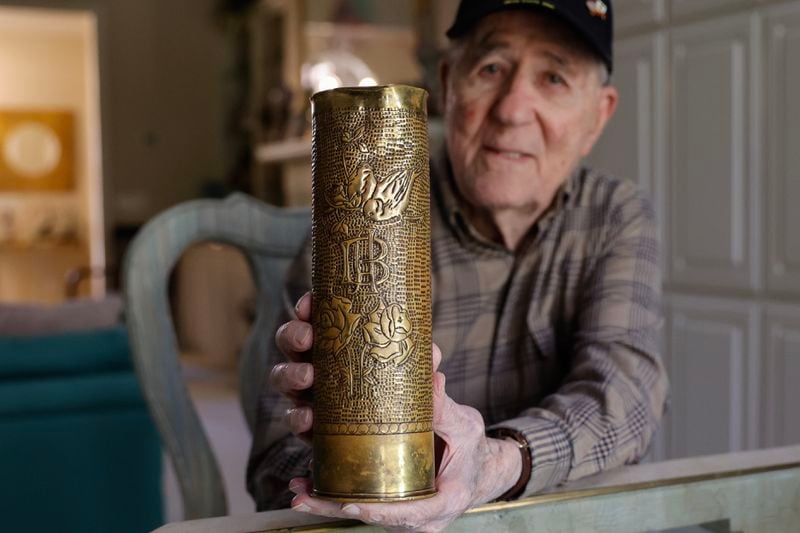 World War II veteran and liberator Hilbert “Hibby” Margol holds a 75 mm howitzer shell casing that he found during the war on Wednesday, Jan. 17, 2024.  (Natrice Miller/ Natrice.miller@ajc.com)