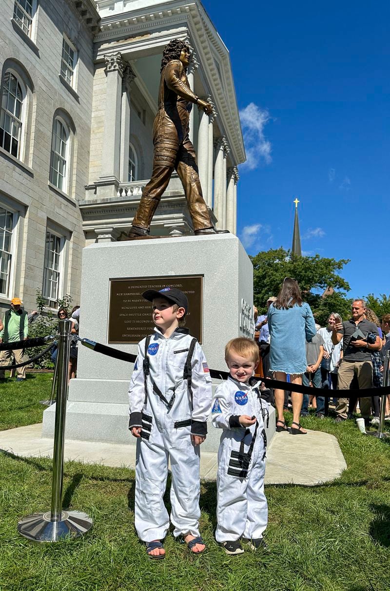 Aspiring astronaut, Ollie Tyrrell, 6, and his brother, Riot Tyrrell, 3, pose in front of the newly-unveiled statue of Christa McAuliffe at the New Hampshire Statehouse, Monday, Sept. 2, 2024, in Concord, N.H. (AP Photo/Holly Ramer)