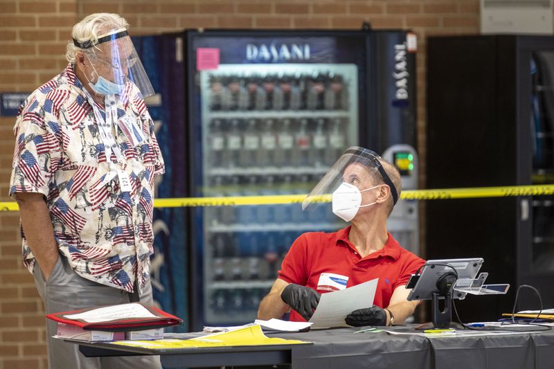 Gwinnett County poll manager Don Heaton (left) speaks with assistant poll manager Bob Portnoy during Georgia primary run-off elections at Norcross High School in Norcross on Aug. 11.. (ALYSSA POINTER / ALYSSA.POINTER@AJC.COM)