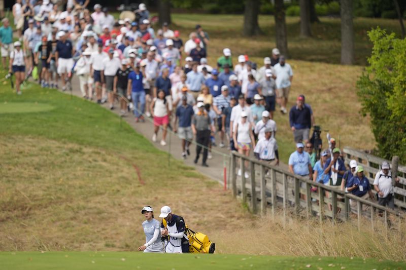 Lydia Ko, bottom left,of New Zealand, walks up the 17th fairway while followed by the crowd during the final round of the LPGA Kroger Queen City Championship golf tournament at TPC River's Bend in Maineville, Ohio, Sunday, Sept. 22, 2024. (AP Photo/Carolyn Kaster)