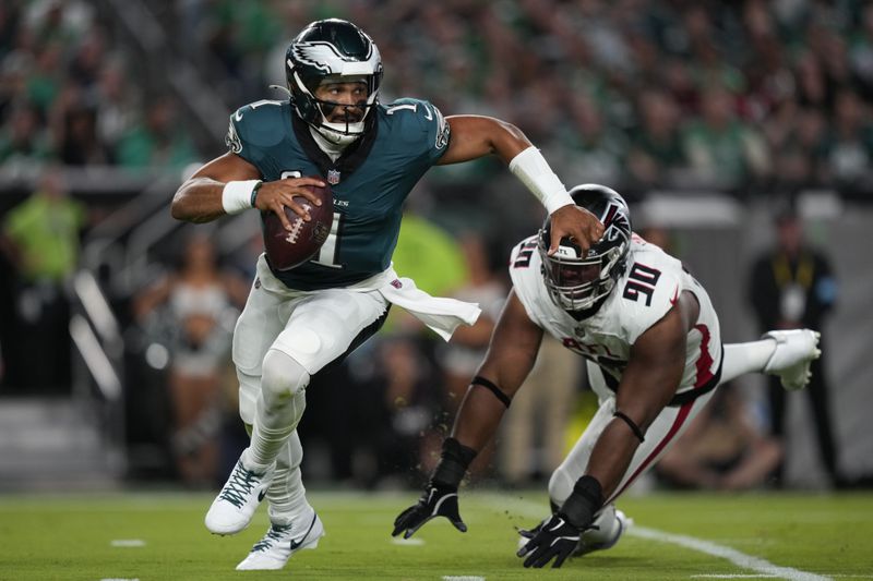 Philadelphia Eagles quarterback Jalen Hurts (1) runs past Atlanta Falcons defensive tackle David Onyemata (90) during the first half of an NFL football game Monday, Sept. 16, 2024, in Philadelphia. (AP Photo/Matt Slocum)