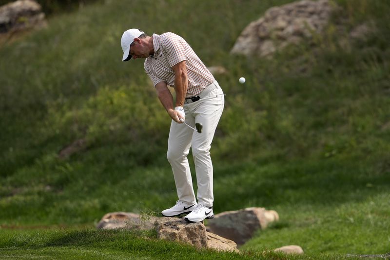 Rory McIlroy, of Northern Ireland, stands on a rock to play his shot in the 17th fairway during the first round of the BMW Championship golf event at Castle Pines Golf Club, Thursday, Aug. 22, 2024, in Castle Rock, Colo. (AP Photo/Matt York)