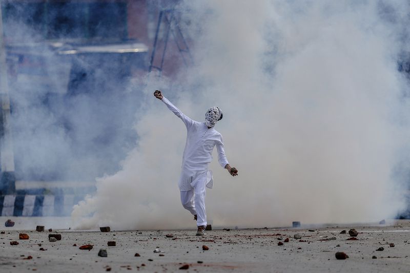 A masked protester throws stone at Indian security forces during a protest after Eid prayers in Srinagar, Indian controlled Kashmir, Saturday, June 16, 2018. (AP Photo/Dar Yasin, File)