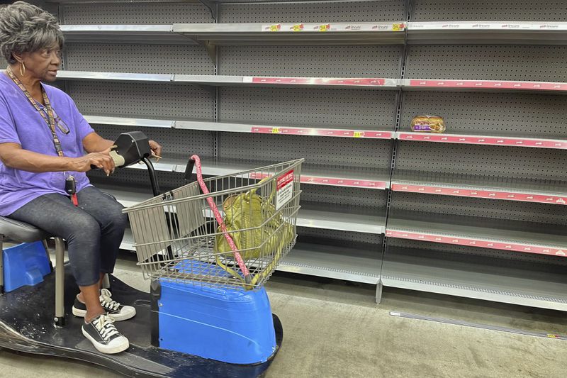 A shopper passes by empty shelves in the bread section of a Walmart, Wednesday, Sept. 25, 2024 in Tallahassee, Fla. Grocery stores and gas stations were seeing heavy traffic in advance of Hurricane Helene, expected to make landfall Thursday night in the Big Bend area. (AP Photo/Phil Sears)