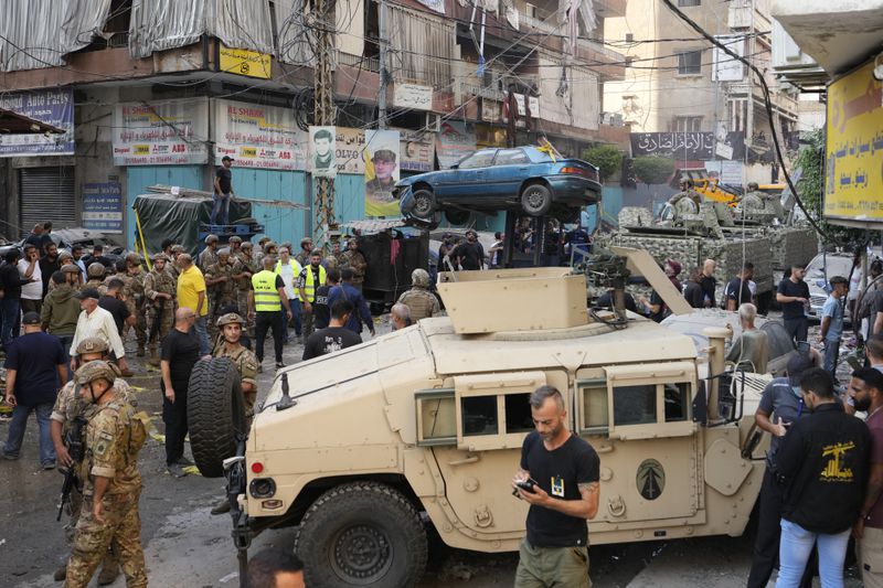 A forklift removes a damaged car as Lebanese army and emergency workers gather at the scene of an Israeli airstrike in Beirut's southern suburbs, Tuesday, Sept. 24, 2024. (AP Photo/Hassan Ammar)