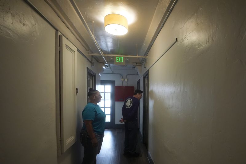 Brandi Marshall, Five Keys director of housing services, left, watches as Donald Siu, property manager, knocks on a resident's door at a Five Keys transitional housing location in San Francisco, Monday, Aug. 26, 2024. (AP Photo/Jeff Chiu)