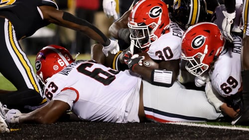 Georgia Bulldogs running back Daijun Edwards (30) scores the go-ahead 1-yard touchdown with help from offensive lineman Sedrick Van Pran (63, left) and Tate Ratledge (69) during the fourth quarter against the Missouri Tigers in a NCAA Football game at Faurot Field at Memorial Stadium, Saturday, October 1, 2022, in Columbia, Mo. Georgia won 26-22. (Jason Getz / Jason.Getz@ajc.com)