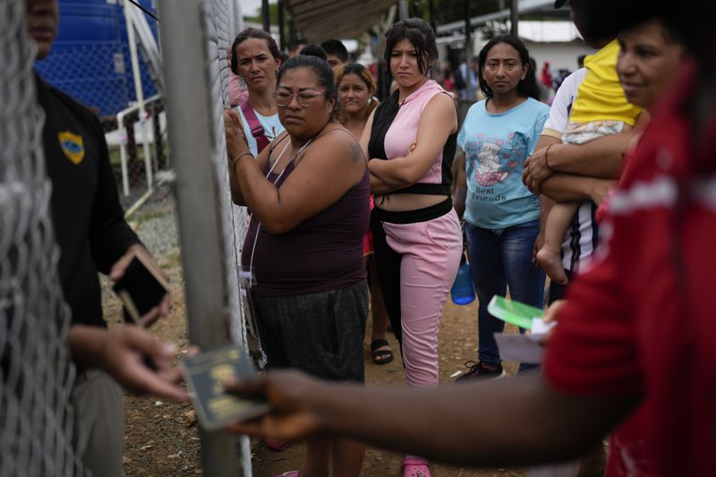 Migrants wait to get back their passports as Panamanian immigration officers process their identifications at a post where those who trekked across the Darién Gap stop along their way north toward the U.S., in Lajas Blancas, Panama, Thursday, Sept. 26, 2024. (AP Photo/Matias Delacroix)