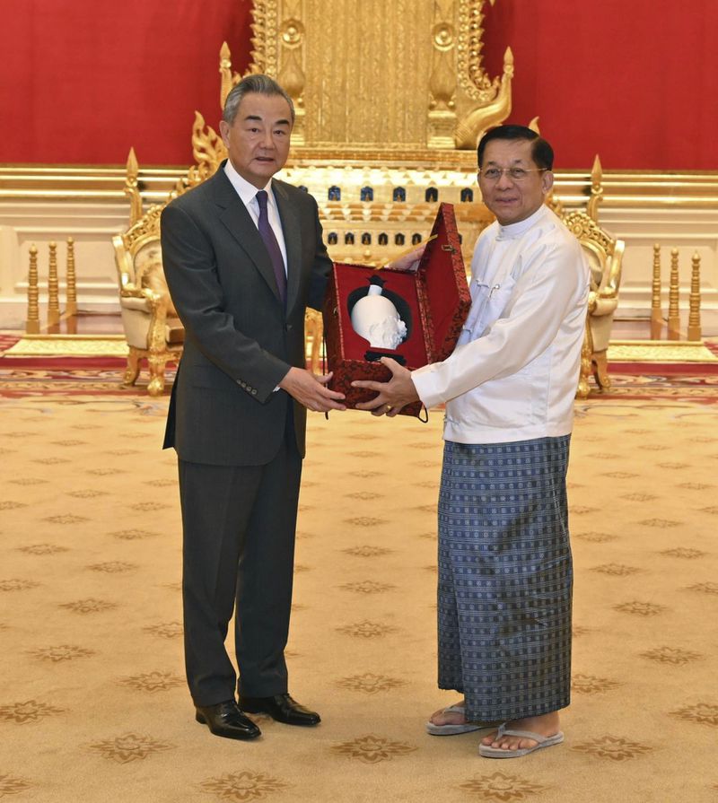 This photo provided by Myanmar Military Information Team, Myanmar's military leader Senior Gen. Min Aung Hlaing, right, chairman of State Administration Council, exchanges gift with Chinese Foreign Minister Wang Yi during their meeting Wednesday, Aug. 14, 2024, in Naypyitaw, Myanmar. (Myanmar Military Information Team via AP)