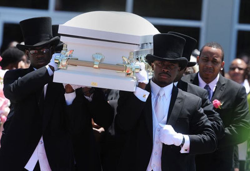 Members of the Willie A Watkins Funeral Home carry the body of 2-year-old Jazmin Green on their shoulders as her father Charles Green walks behind.