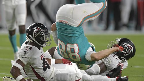 Miami Dolphins tight end Mike Gesicki (88) flips over two Atlanta Falcons defenders after catching a pass in the first half in a preseason game at Hard Rock Stadium in Miami Gardens, Florida, on Saturday, Aug. 21, 2021. The Dolphins won, 37-17. (Michael Laughlin/South Florida Sun Sentinel/TNS)