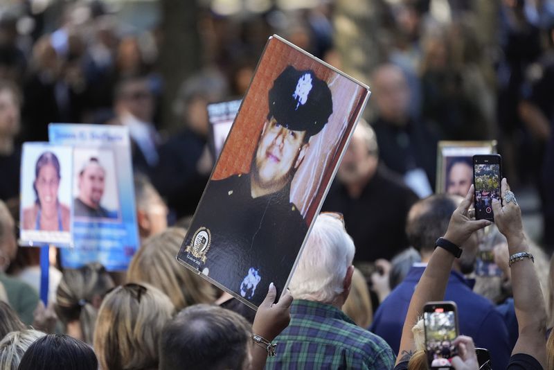 A woman holds up a photo of a New York City Police officer during the 9/11 Memorial ceremony on the 23rd anniversary of the Sept. 11, 2001 terror attacks, Wednesday, Sept. 11, 2024, in New York. (AP Photo/Pamela Smith)