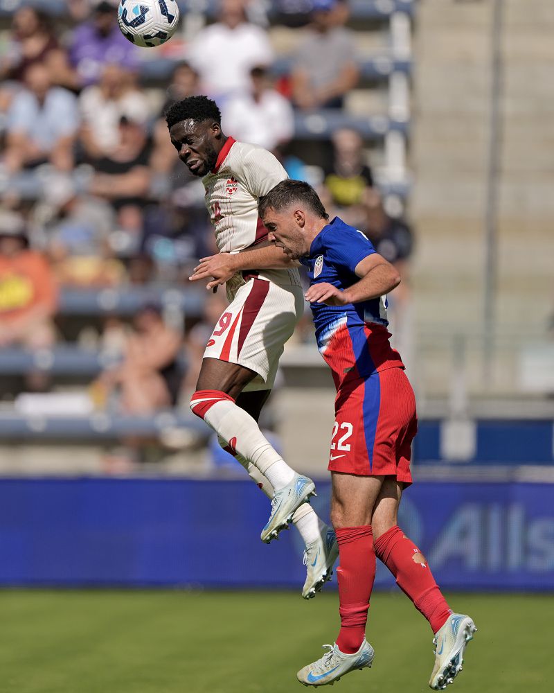 Canada defender Alphonso Davies beats United States defender Joe Scally (22) to the ball during the first half of an international friendly soccer game, Saturday, Sept. 7, 2024, in Kansas City, Mo. (AP Photo/Charlie Riedel)