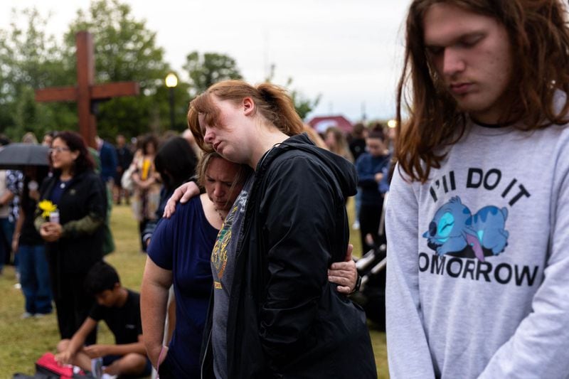 Amber Brewster, middle, embraces Heidi Meyer alongside Adrian Meyer in mourning at a vigil at Jug Tavern Park in Winder on Friday. (Arvin Temkar/The Atlanta Journal-Constitution)