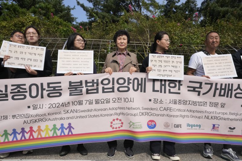 Han Tae-soon, center, attends a press conference in front of the Seoul Central District Court in Seoul, South Korea, Monday, Oct. 7, 2024 before she sues her government, an adoption agency and an orphanage over the adoption of her daughter. The banner reads "Lawsuit for state compensation on the illegal adoption of a missing child." (AP Photo/Ahn Young-joon)