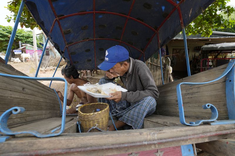 Local resident eat meal on a cart near a flooded road in Naypyitaw, Myanmar, Saturday, Sept. 14, 2024. (AP Photo/Aung Shine Oo)