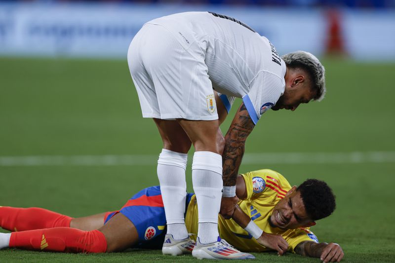 Colombia's Luis Diaz is helped by Uruguay's Giorgian De Arrascaeta after being injured during a Copa America semifinal soccer match in Charlotte, N.C., Wednesday, July 10, 2024. (AP Photo/Nell Redmond)