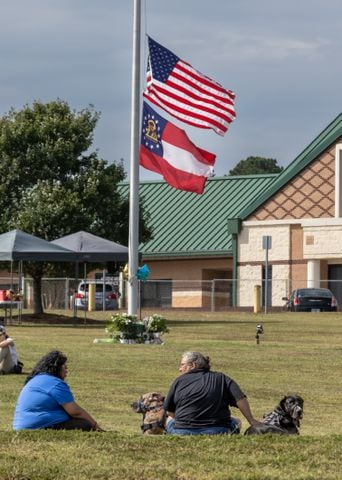 Betsy Chapeau (left) and her mother, former Athens police officer, Michelle Chapeau (right) sit in front of Apalachee High School on Thursday with their two great Dane therapy dogs which were put into service for grieving students at the school and intern. Students and well wishers arrived with flowers to place at the flag pole at Apalachee High School in Winder on Thursday, Sept. 5, 2024. A 14-year-old is accused of shooting and killing two fellow students and two teachers and injuring nine others at Apalachee High School on Wednesday. (John Spink/AJC)