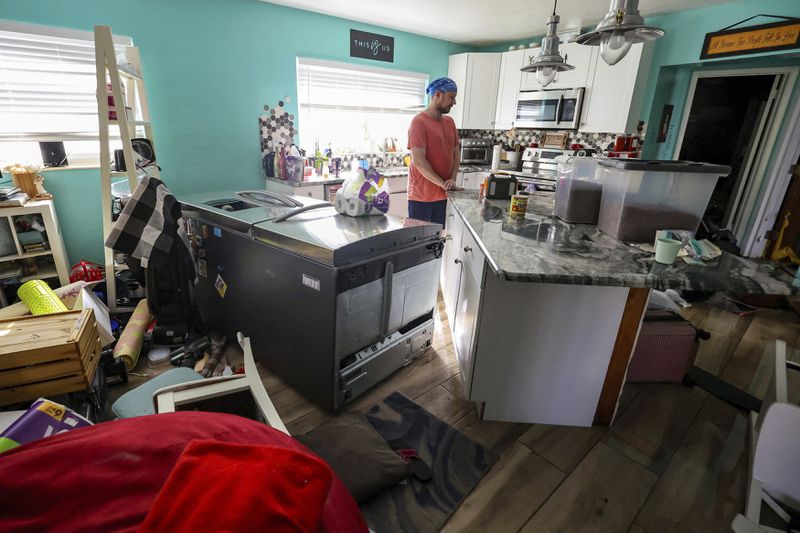 Bradley Tennant looks through his house flooded with water from Hurricane Helene in the Shore Acres neighborhood Friday, Sept. 27, 2024, in St. Petersburg, Fla. (AP Photo/Mike Carlson)