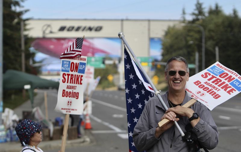 Union machinist Bill Studerus holds a picket sign and an American flag near Boeing's factory in Everett, Washington, Thursday, Sept. 19, 2024. (AP Photo/Manuel Valdes)