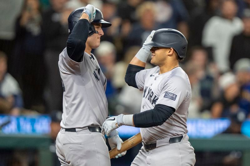 New York Yankees' Jasson Dominguez, right, celebrates with Anthony Rizzo after hitting a solo home run during the fifth inning of a baseball game against the Seattle Mariners, Tuesday, Sept. 17, 2024, in Seattle. (AP Photo/Stephen Brashear)