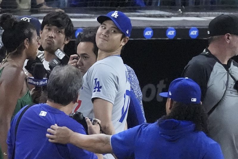 Los Angeles Dodgers' Shohei Ohtani, of Japan, smiles at teammates as he does a postgame interview after a baseball game against the Miami Marlins, Thursday, Sept. 19, 2024, in Miami. (AP Photo/Wilfredo Lee)