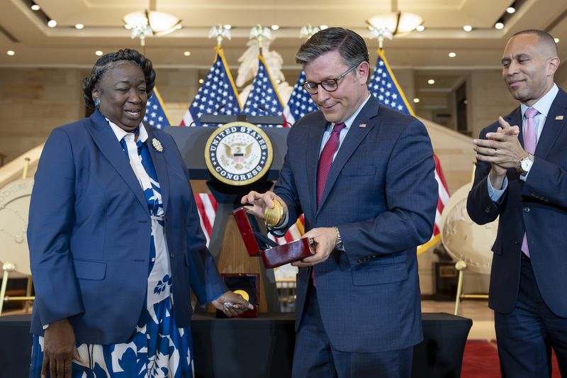 House Speaker Mike Johnson, R-La., reacts after dropping a Congressional Gold Medal while posing for a photograph with NASA's Johnson Space Center Senior Apollo Sample Processor and Lab Manager Andrea Mosie, left, at a Congressional Gold Medal ceremony to honor the Black women mathematicians of NASA who contributed to the space race and who were the subject of the book and movie "Hidden Figures," at the Capitol in Washington, Wednesday, Sept. 18, 2024. House Minority Leader Hakeem Jeffries, D-N.Y., watches at right. (AP Photo/J. Scott Applewhite)