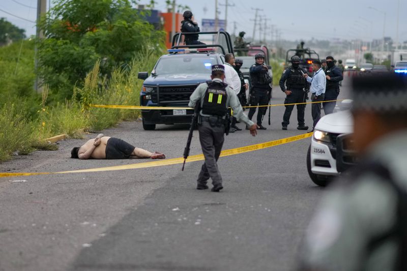 Law enforcement officials rope off an area where a body was found lying on the side of a road in Culiacan, Sinaloa state, Mexico, Saturday, Sept. 21, 2024. (AP Photo/Eduardo Verdugo)