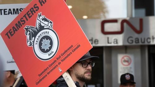 Rail workers picket in front of Canadian National headquarters on the first day of a nationwide rail shutdown, after workers were locked out by CN and CPKC when new contract agreements weren't reached by the midnight deadline, in Montreal, Thursday, Aug. 22, 2024. (Ryan Remiorz /The Canadian Press via AP)