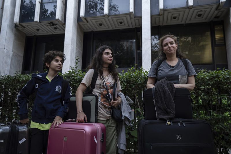 Greek citizens, Dolan Tabri, right, with her children Adrianna, center and Adam , stand outside a Greek Foreign ministry building in central Athens on Thursday, Oct. 3, 2024, after they were evacuated with a Greek military transport aircraft from Lebanon.(AP Photo/Petros Giannakouris)