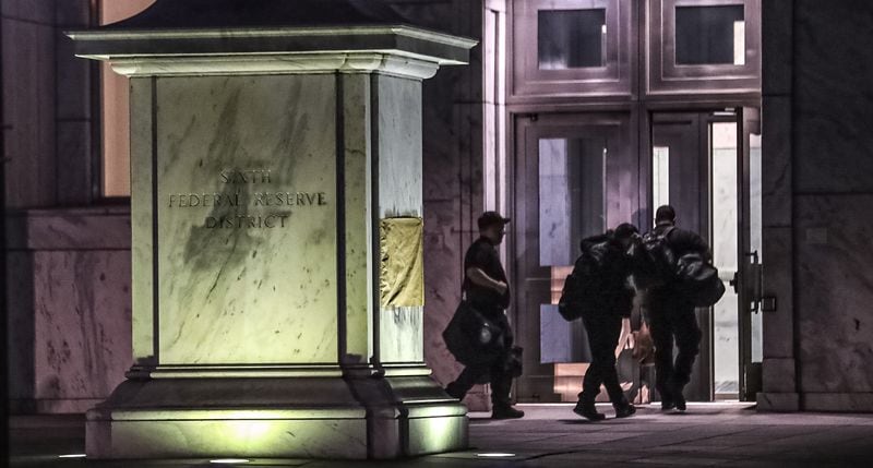 One side of a stone marker at the Federal Reserve Bank of Atlanta was scrubbed clean of graffiti on Friday morning, while the other was covered by paper during an investigation into overnight vandalism at the federal building and the nearby rainbow crosswalk in Midtown Atlanta.