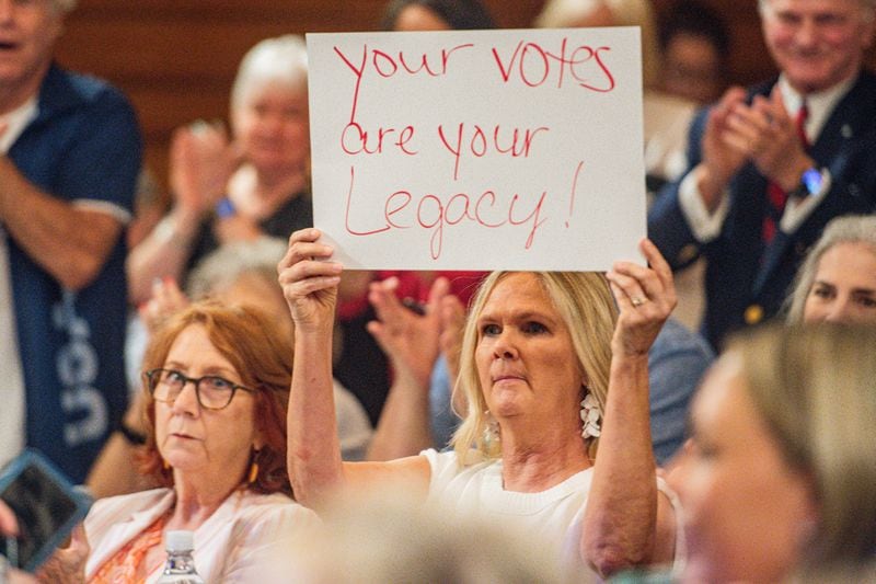 An audience member holds a sign during a State Election Board meeting in Atlanta on Tuesday, July 9, 2024.  (Ziyu Julian Zhu / AJC)