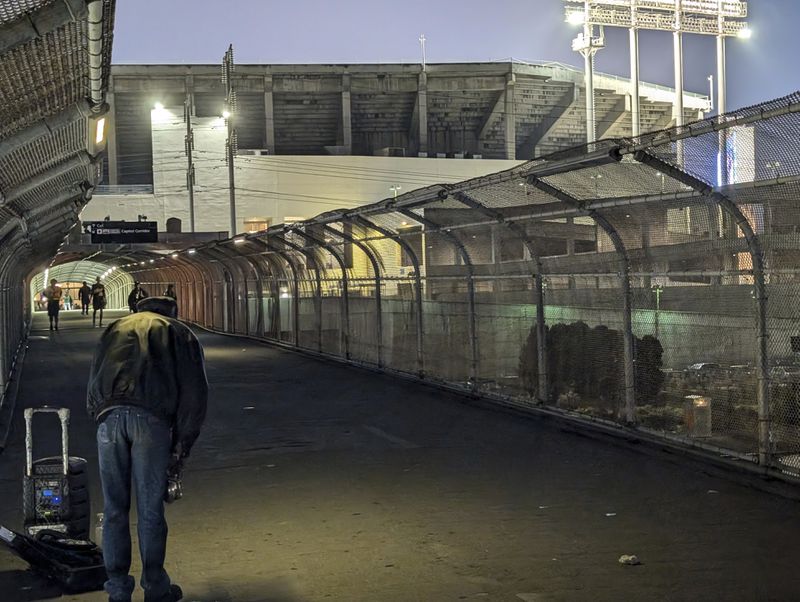 An Oakland A's fan plays his saxophone during an Aug. 6, 2024, game while standing outside the Oakland Coliseum on a ramp that connects the regions's public transit system with the stadium in Oakland, Calif.. (AP Photo/Michael Liedtke)