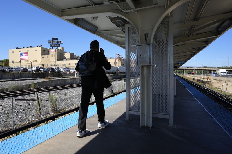 A pedestrian talks on his cell phone as he arrives at the Chicago Transit Authority Blue Line Harlem Ave., train station Tuesday, Sept. 3, 2024, in Forest Park, Ill. (AP Photo/Charles Rex Arbogast)