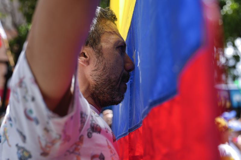 A man holds up a Venezuelan national flag during a rally to protest official results that declared President Nicolas Maduro the winner of the July presidential election, in Caracas, Venezuela, Saturday, Aug. 17, 2024. (AP Photo/Ariana Cubillos)