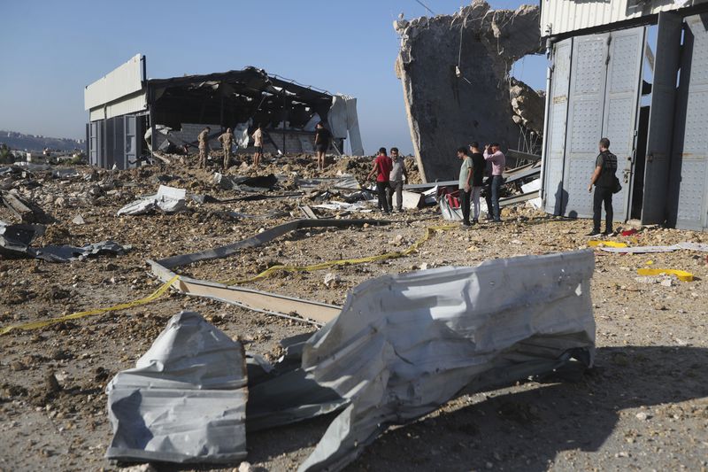 People gather near the site of an Israeli airstrike that hit a hangar in the southern town of Jiyeh, Lebanon, Wednesday, Sept. 25, 2024. (AP Photo/Mohammed Zaatari)