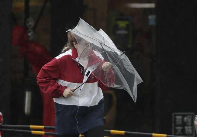 A woman struggles with winds generated by Typhoon Krathon in Kaohsiung, Southern Taiwan, Wednesday, Oct. 2, 2024. (AP Photo/Chiang Ying-ying)