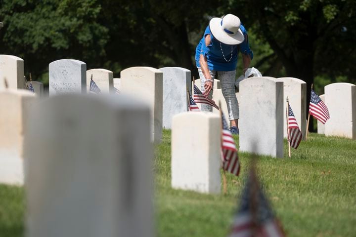 Connie Long Michael fixes the flag in front of her mother’s grave at Marietta National Cemetery before the Memorial Day ceremony on Monday, May 27, 2024. Michael’s mother attended the ceremony every year with her until she died in September. Micheal’s father, who is buried next to her mother, was a Naval aviator who died in a plane crash near Cedartown. (Ben Gray / Ben@BenGray.com)